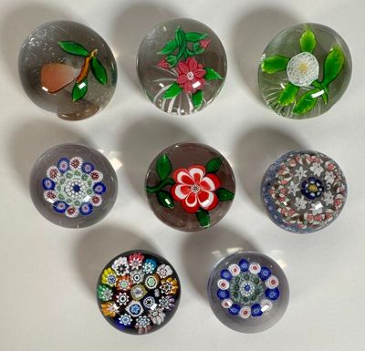 six glass marbles with different designs on them sitting on a white surface