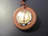 une petite montre de poche avec un bracelet en cuir, posée sur une table