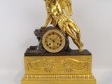 a gold clock with a statue on top of it