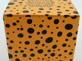 an orange box with black dots on it sitting on a white surface