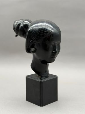 sculpture d'une tête de femme sur un socle en marbre noir
