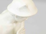 a white figurine of a woman with a hat on