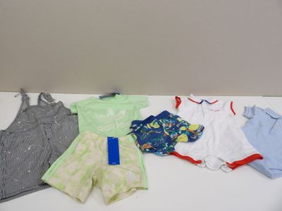 une pile de vêtements de bébé posée sur une table à côté d'un téléphone portable