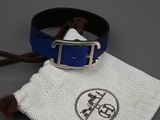 une ceinture en cuir bleu avec une boucle argentée et une pochette en tissu blanc