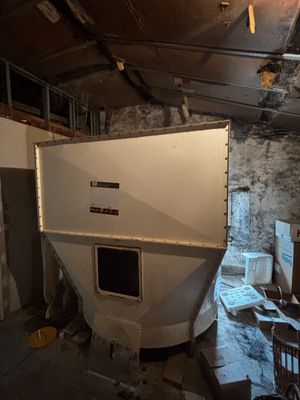 un grand bateau blanc posé dans une pièce remplie de bric-à-brac
