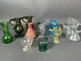 de nombreux vases et verres en verre de différentes couleurs sur la table