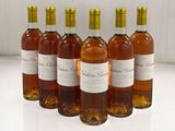 six bouteilles de vin sont alignées sur une surface blanche