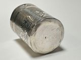 a silver cup that is sitting on a white surface