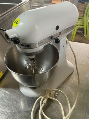 a white mixer sitting on a table next to a metal bowl