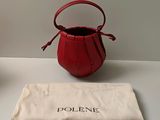 un petit sac à main rouge posé sur une table à côté d'un sac
