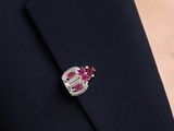 a close up of a person wearing a suit with a pink and white broocher