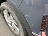 a person holding a ruler next to a car ' s tire
