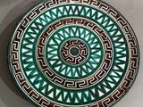 green and brown decorative plate with geometric design on white surface