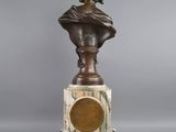 a bronze bust of a woman on a marble pedestal
