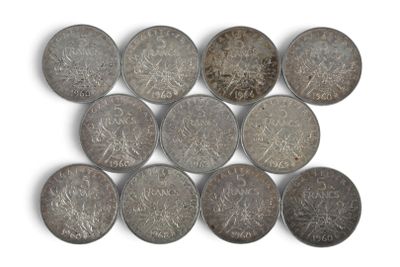 Plusieurs pièces anciennes sont disposées en rangée sur une surface blanche