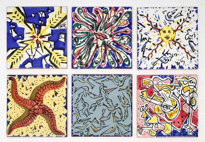 quatre carreaux de couleurs différentes, ornés de motifs variés, posés sur une surface blanche