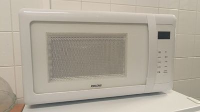 un micro-ondes blanc posé sur une machine à laver