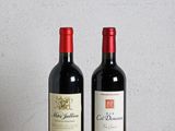 deux bouteilles de vin posées sur une table en bois à côté d'une bouteille de vin