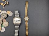a lot of coins and a watch sitting on a table