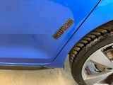 a cat that is sitting on the tire of a blue car