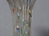 a glass vase with flowers painted on it on a table