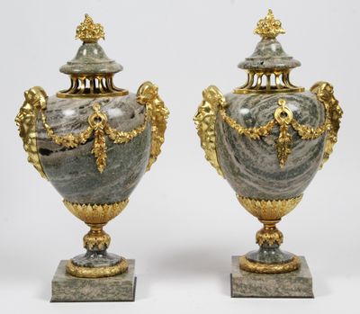 une paire de vases en argent et en or posés sur des socles, sur fond blanc