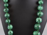 a green beaded necklace on a black mannequin