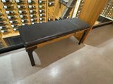 un banc avec une assise en cuir noir, placé devant un casier à bouteilles