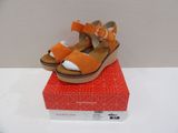 orange and white sandals on top of a red box on a white surface