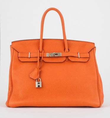 un sac à main en cuir orange muni d'un cadenas sur la poignée