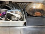 des casseroles et des poêles sont posées sur une étagère en métal dans une cuisine