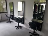 a photo of a hair salon with chairs and mirrors