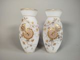 two white vases with gold designs on them