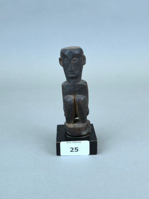 une petite statue en bois représentant un homme assis sur un socle noir