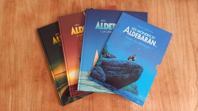 three books on a table with a wooden table top