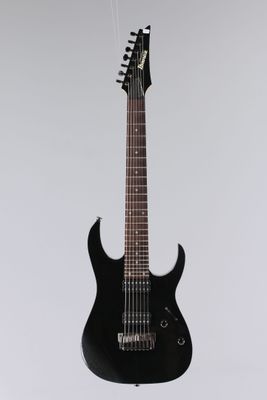une guitare électrique noire suspendue à une ficelle sur un mur blanc
