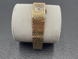 an image of a gold watch on a white ring on a table