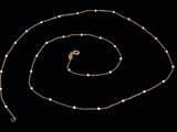 un collier en or avec des perles et une chaîne sur fond noir