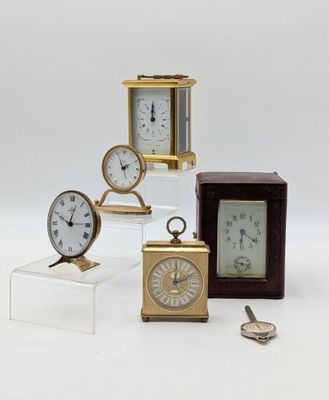 several different types of clocks on display on a white surface