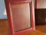 two picture frames sitting on a table with a white wall in the background