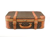 une valise marron et beige posée sur une surface blanche
