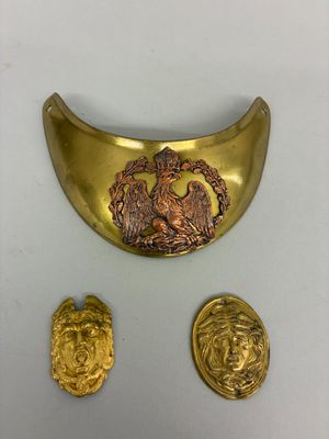 une plaque en or sur laquelle est représenté un lion, à côté de deux autres pièces d'or