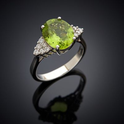 a close up of a ring with a peridot stone and diamonds