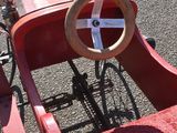 a red pedal car with a steering and a steering wheel
