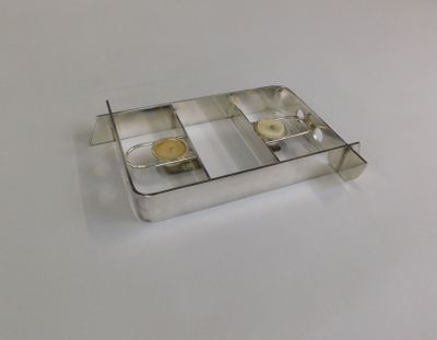 un plateau en argent sur lequel sont posées deux bougies, posé sur une table blanche