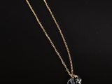 un collier en or orné d'un pendentif en forme de cheval sur fond noir