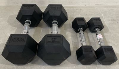 three black rubber dumbbells and a pair of black rubber dumbbells on a tile floor