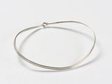 gros plan d'un bracelet en argent sur une surface blanche