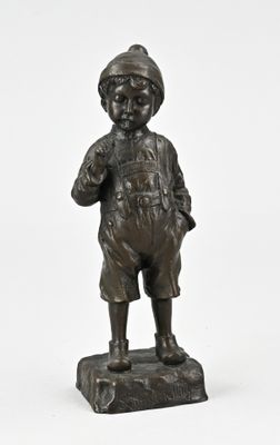 statue en bronze représentant un garçon coiffé d'un chapeau, debout sur un rocher