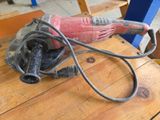 Quelqu'un utilise une ponceuse sur une table en bois pour poncer un morceau de bois.
